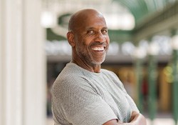 Man in gray shirt smiling outside