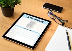 Dental insurance form on tablet next to office supplies