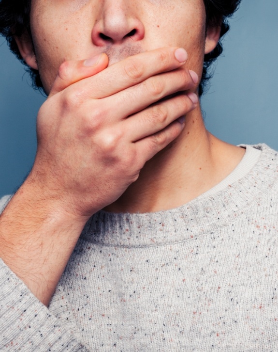 Person in need of emergency dentistry covering mouth