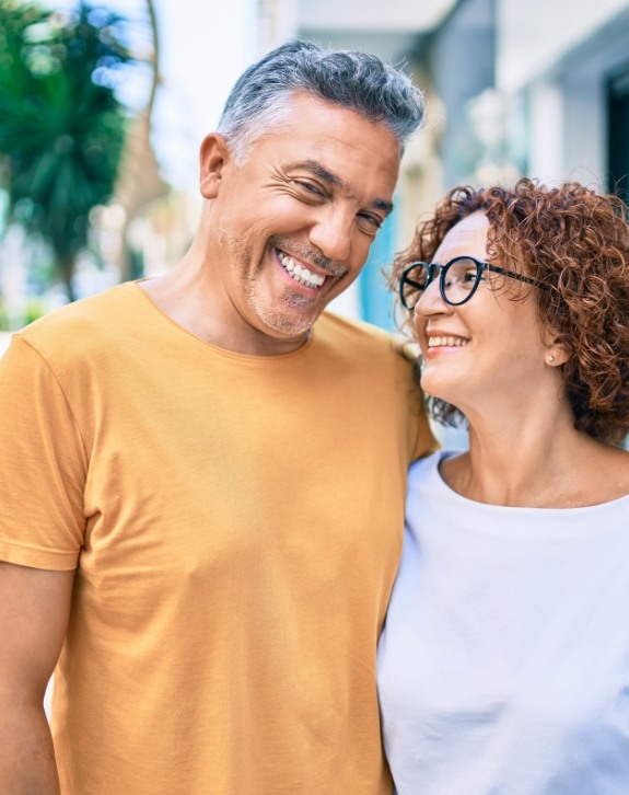 Man and woman smiling after tooth replacement with dental implants