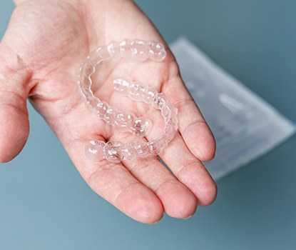 person holding two clear aligners