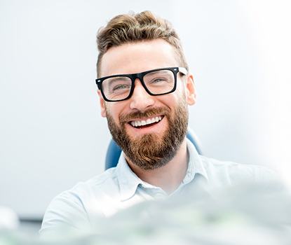 man smiling while sitting in dental chair 