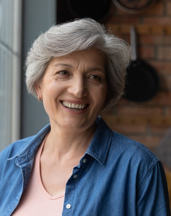 Older woman smiling after replacing missing teeth