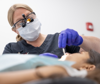 Children's dentist providing dental checkup and teeth cleaning for kids