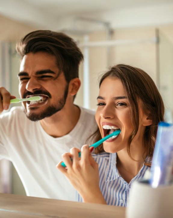 Man and woman brushing teeth before preventive dentistry visit