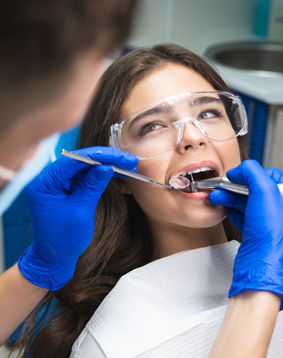 Woman in protective glasses undergoing root canal procedure