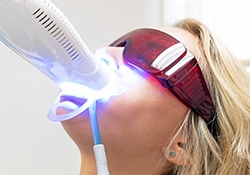 Woman having teeth whitened in dental office