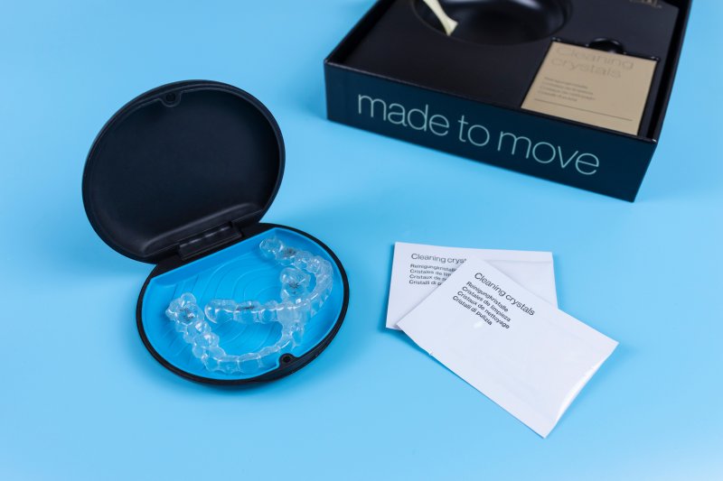 Invisalign aligners next to a packet of cleaning crystals
