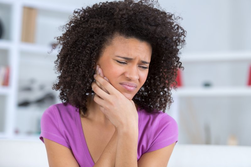 woman holding her jaw due to dental emergencies