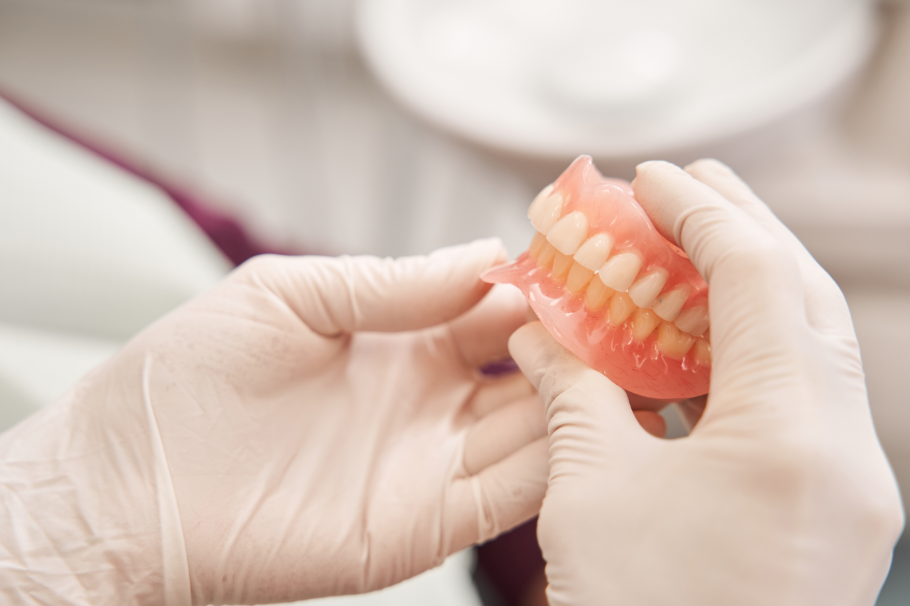 Gloved hands holding dentures